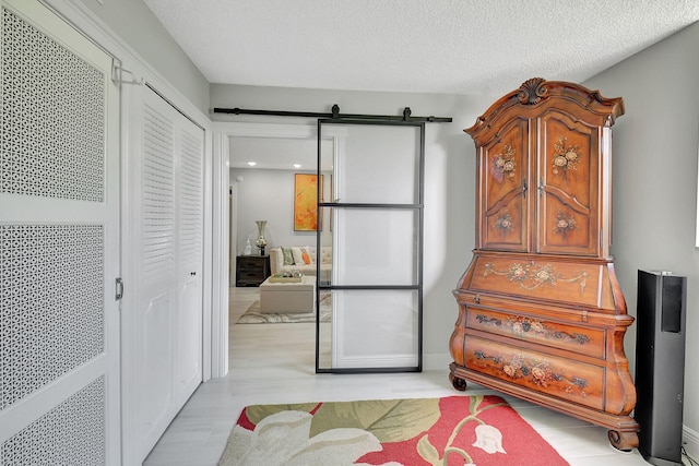 bedroom with a textured ceiling, a barn door, and a closet