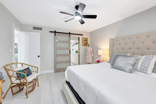bedroom featuring a barn door, visible vents, ceiling fan, baseboards, and light wood-style floors