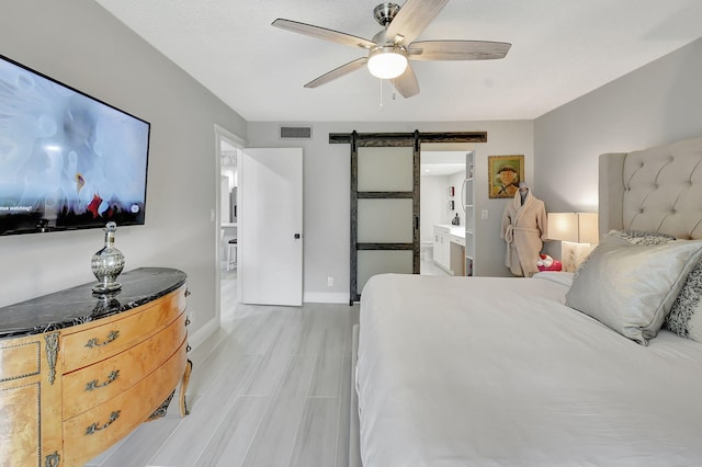 bedroom with ceiling fan, a barn door, visible vents, baseboards, and light wood-type flooring