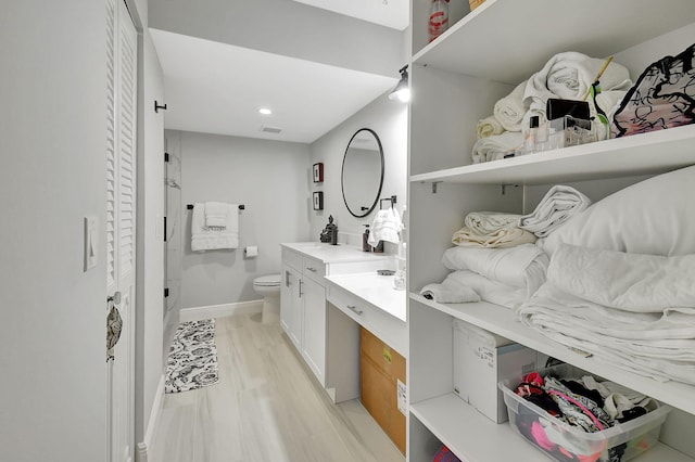 bathroom with toilet, wood finished floors, a closet, and vanity