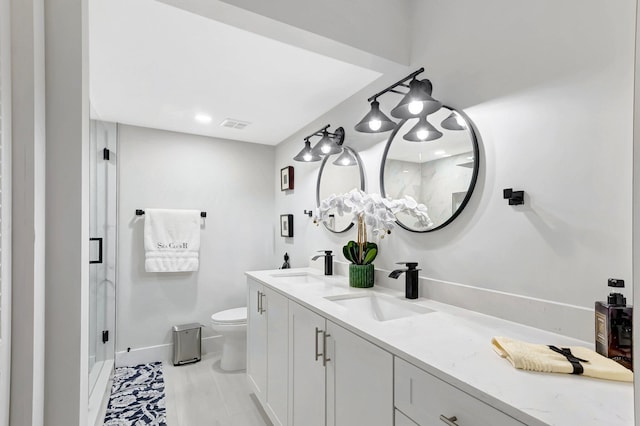 bathroom with toilet, baseboards, double vanity, and a sink