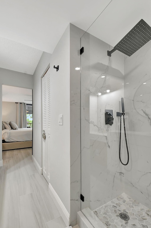 ensuite bathroom featuring ensuite bathroom, a closet, a marble finish shower, and baseboards