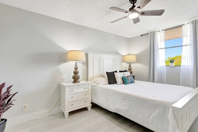 bedroom with a ceiling fan, light wood-style flooring, and a textured ceiling