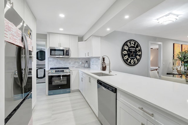 kitchen featuring stacked washer / dryer, a sink, stainless steel appliances, backsplash, and recessed lighting