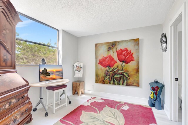 bedroom featuring a textured ceiling, a ceiling fan, light wood-style floors, baseboards, and ensuite bath