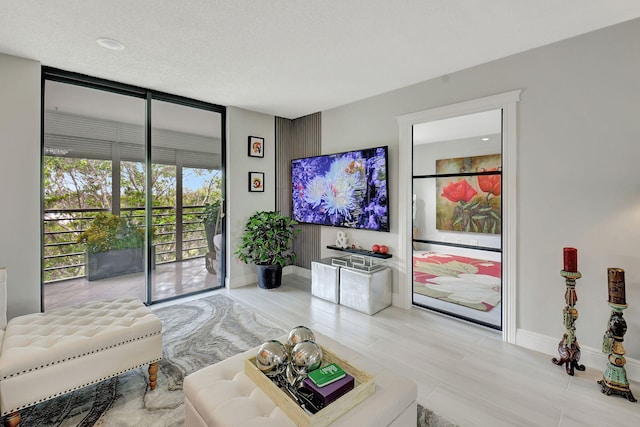 living room with a textured ceiling, baseboards, and floor to ceiling windows