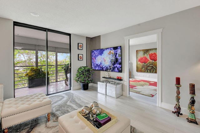 living area featuring a wall of windows, a textured ceiling, and baseboards