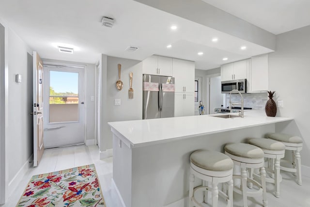 kitchen with a peninsula, appliances with stainless steel finishes, baseboards, and white cabinetry