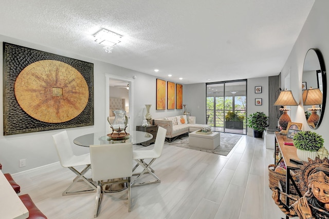 dining room with recessed lighting, a textured ceiling, a wall of windows, light wood-type flooring, and baseboards