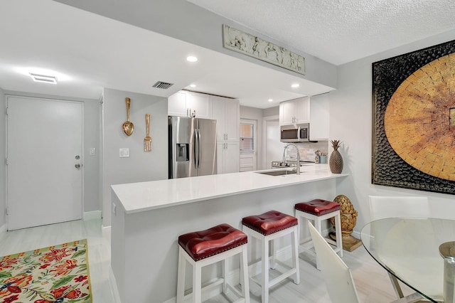 kitchen featuring appliances with stainless steel finishes, visible vents, white cabinets, and a peninsula