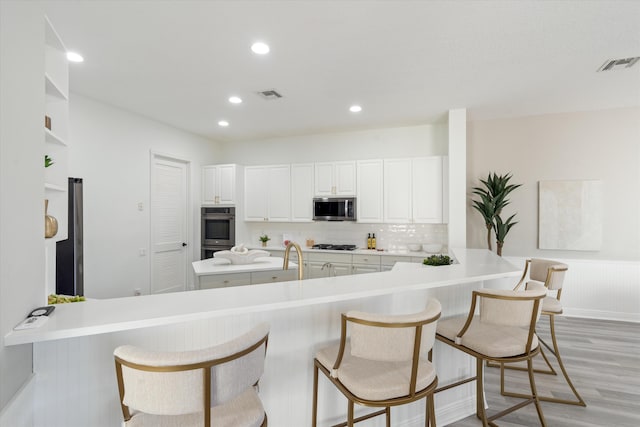 kitchen featuring light countertops, appliances with stainless steel finishes, a peninsula, and visible vents