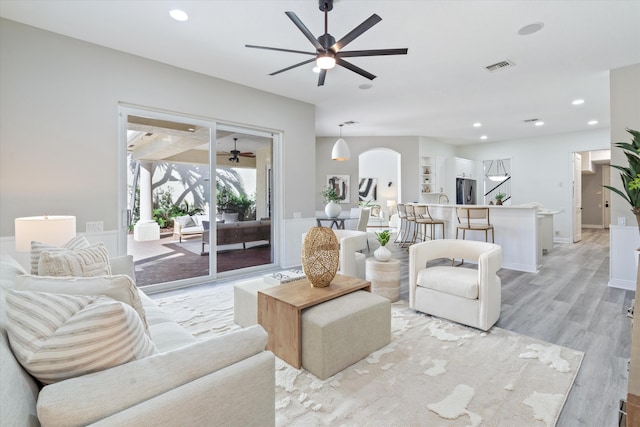 living room featuring visible vents, arched walkways, a ceiling fan, light wood-style floors, and recessed lighting