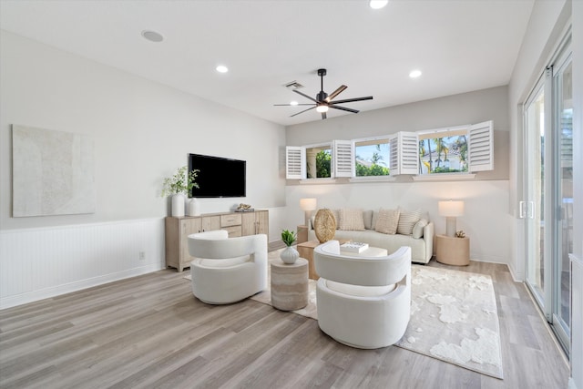 living room featuring a wainscoted wall, visible vents, plenty of natural light, and light wood-style flooring