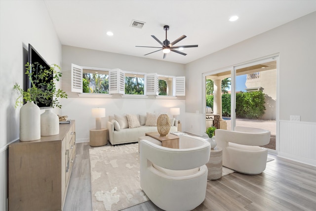 living area with a wainscoted wall, visible vents, light wood finished floors, and recessed lighting