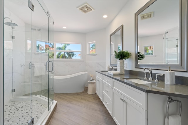 full bathroom with a soaking tub, visible vents, and a sink