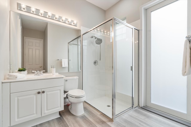 bathroom with a stall shower, vanity, toilet, and wood finished floors