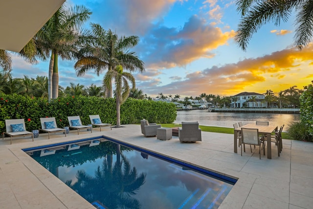 view of swimming pool featuring a patio, a fenced in pool, and a water view