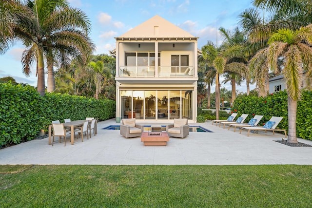 back of house featuring a balcony, a lawn, a patio, and a sunroom