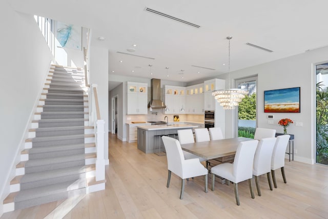 dining space featuring baseboards, visible vents, an inviting chandelier, stairs, and light wood-type flooring