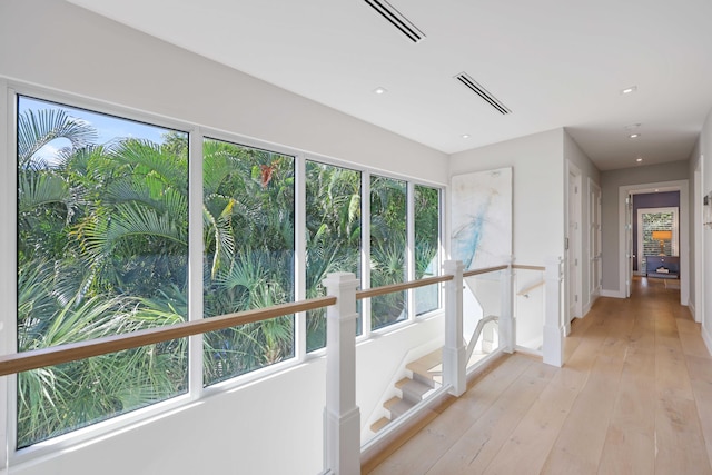 corridor with visible vents, an upstairs landing, baseboards, and light wood finished floors