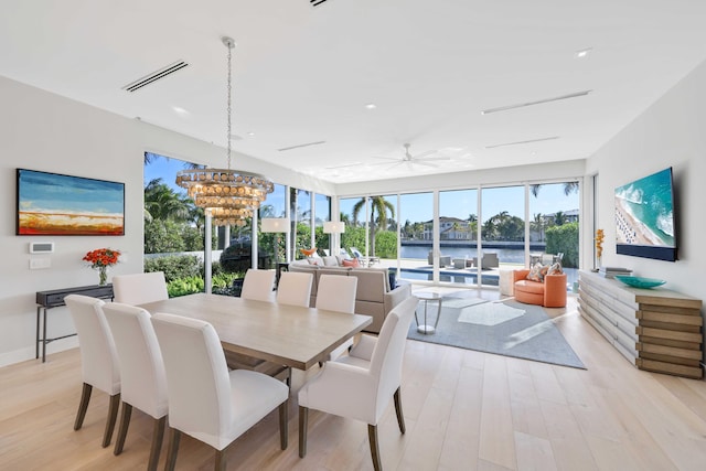 dining area featuring light wood finished floors, visible vents, a chandelier, and baseboards