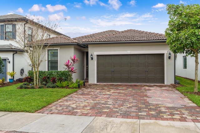 view of front facade with decorative driveway, stucco siding, an attached garage, a tiled roof, and a front lawn