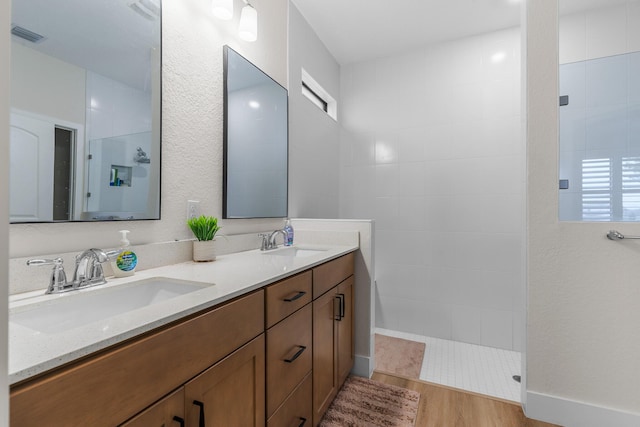 full bathroom featuring double vanity, walk in shower, a sink, and wood finished floors