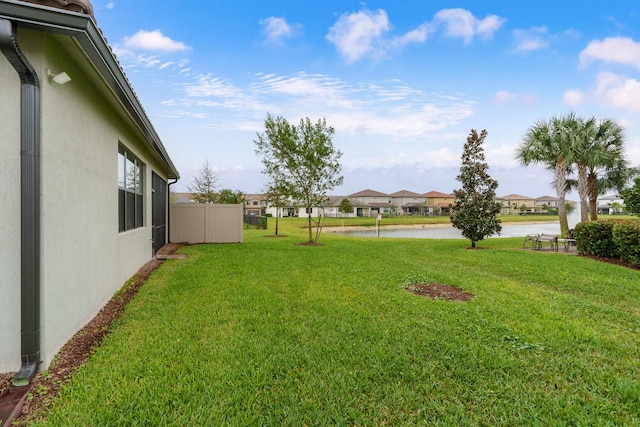 view of yard featuring a water view, a residential view, and fence