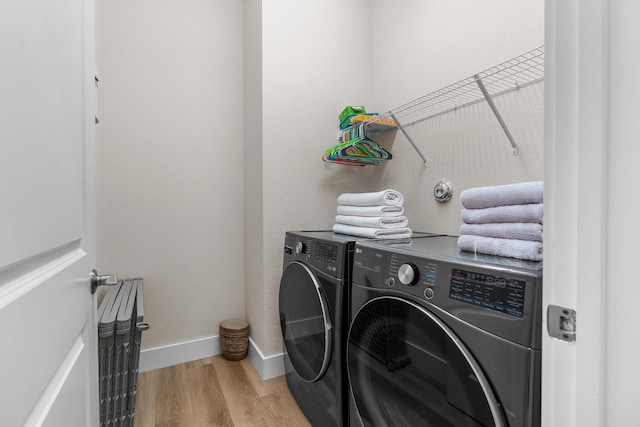 laundry room featuring laundry area, light wood-type flooring, independent washer and dryer, and baseboards