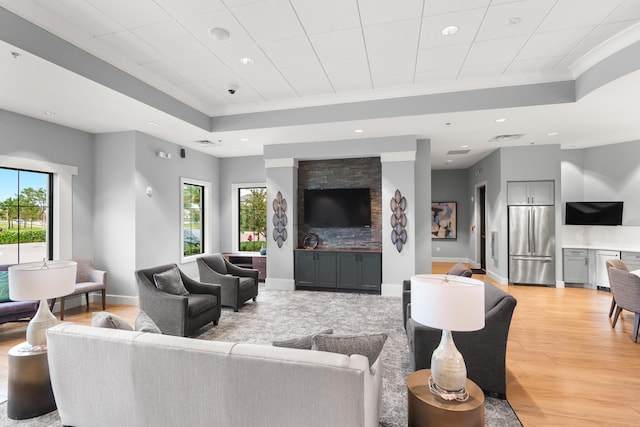 living room with baseboards, visible vents, a tray ceiling, light wood-style floors, and recessed lighting