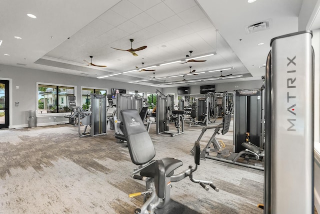 exercise room with ceiling fan, recessed lighting, visible vents, baseboards, and a raised ceiling