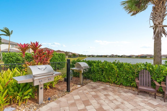 view of patio / terrace with grilling area, a water view, and fence