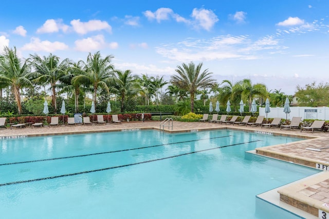 community pool with a patio area and fence