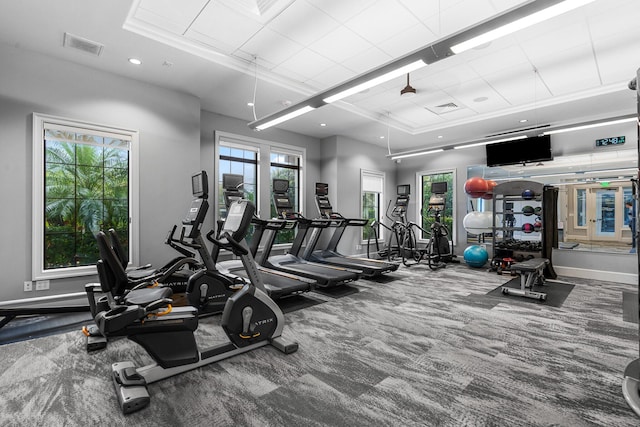 workout area featuring carpet floors, a tray ceiling, recessed lighting, visible vents, and baseboards