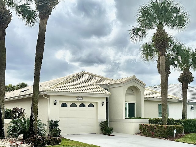 view of front of home with a garage, driveway, a tile roof, and stucco siding