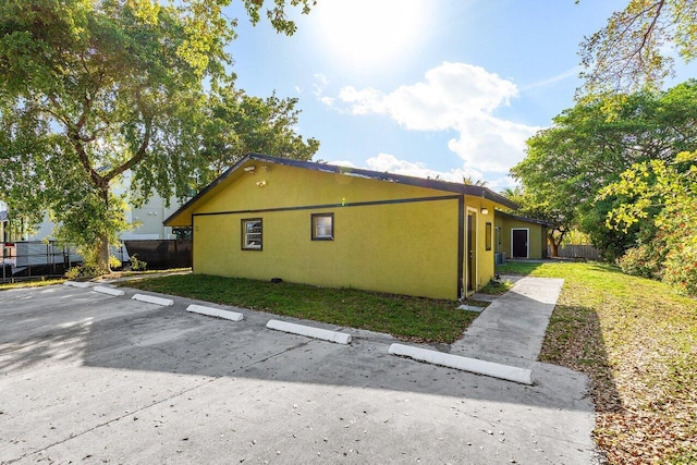 view of property exterior with uncovered parking, fence, and stucco siding