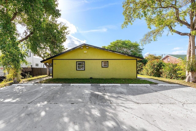 view of side of property with uncovered parking, fence, and stucco siding