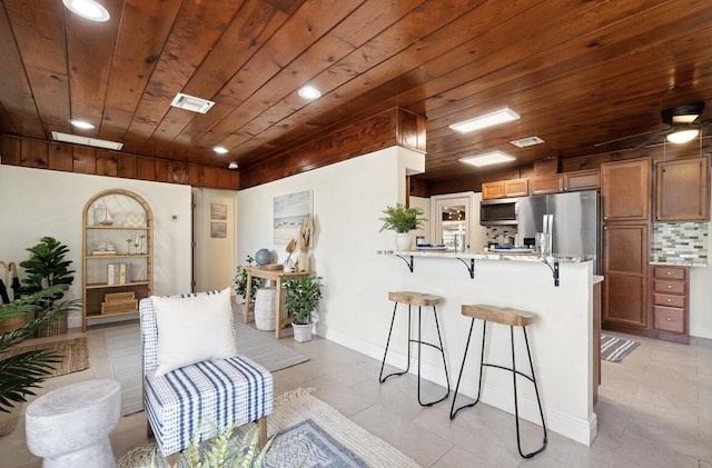 kitchen featuring a breakfast bar, brown cabinets, visible vents, appliances with stainless steel finishes, and a peninsula