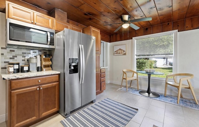 kitchen featuring light tile patterned floors, wood ceiling, light stone counters, stainless steel appliances, and backsplash