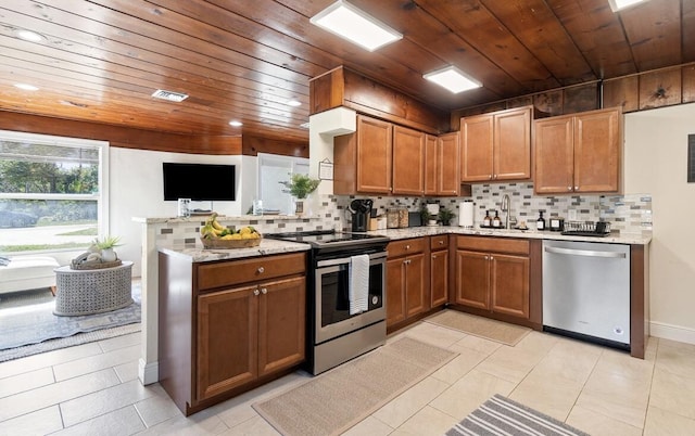 kitchen featuring visible vents, brown cabinetry, decorative backsplash, stainless steel appliances, and a sink