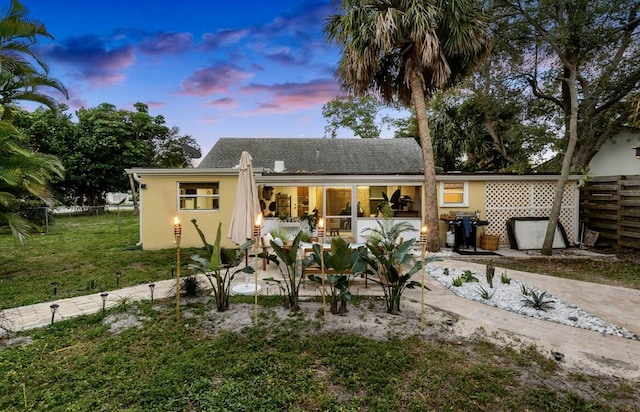 back of property with a lawn, a patio area, fence, and stucco siding