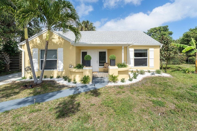 view of front of house with roof with shingles, a porch, a front lawn, and stucco siding