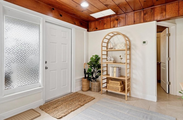 entryway featuring wooden ceiling, light tile patterned floors, and baseboards