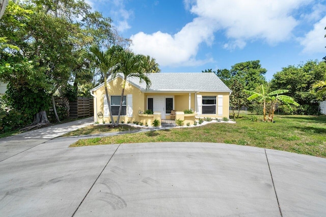 view of front facade featuring driveway, a front yard, fence, and stucco siding