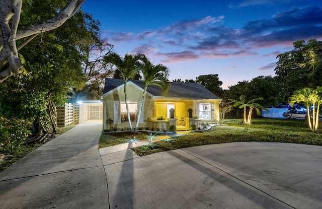 view of front facade featuring concrete driveway, a lawn, fence, and stucco siding