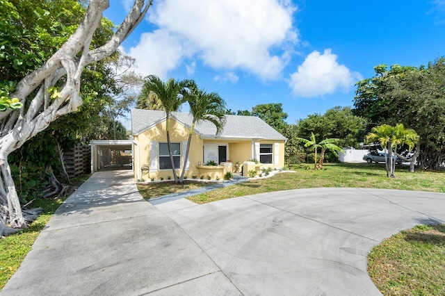 ranch-style house with driveway, a carport, a front yard, and stucco siding