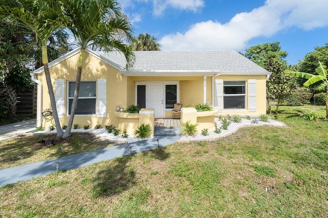 view of front of property featuring a front yard, roof with shingles, and stucco siding