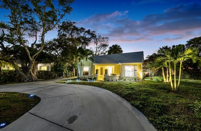 view of front facade with concrete driveway and a lawn