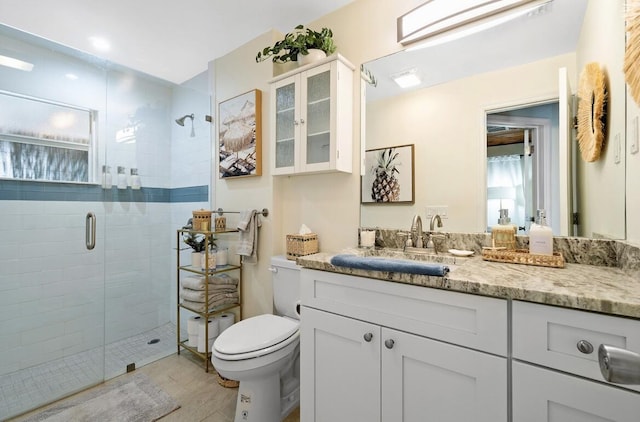 full bathroom with toilet, a stall shower, and vanity