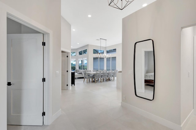 hall featuring a chandelier, baseboards, and recessed lighting